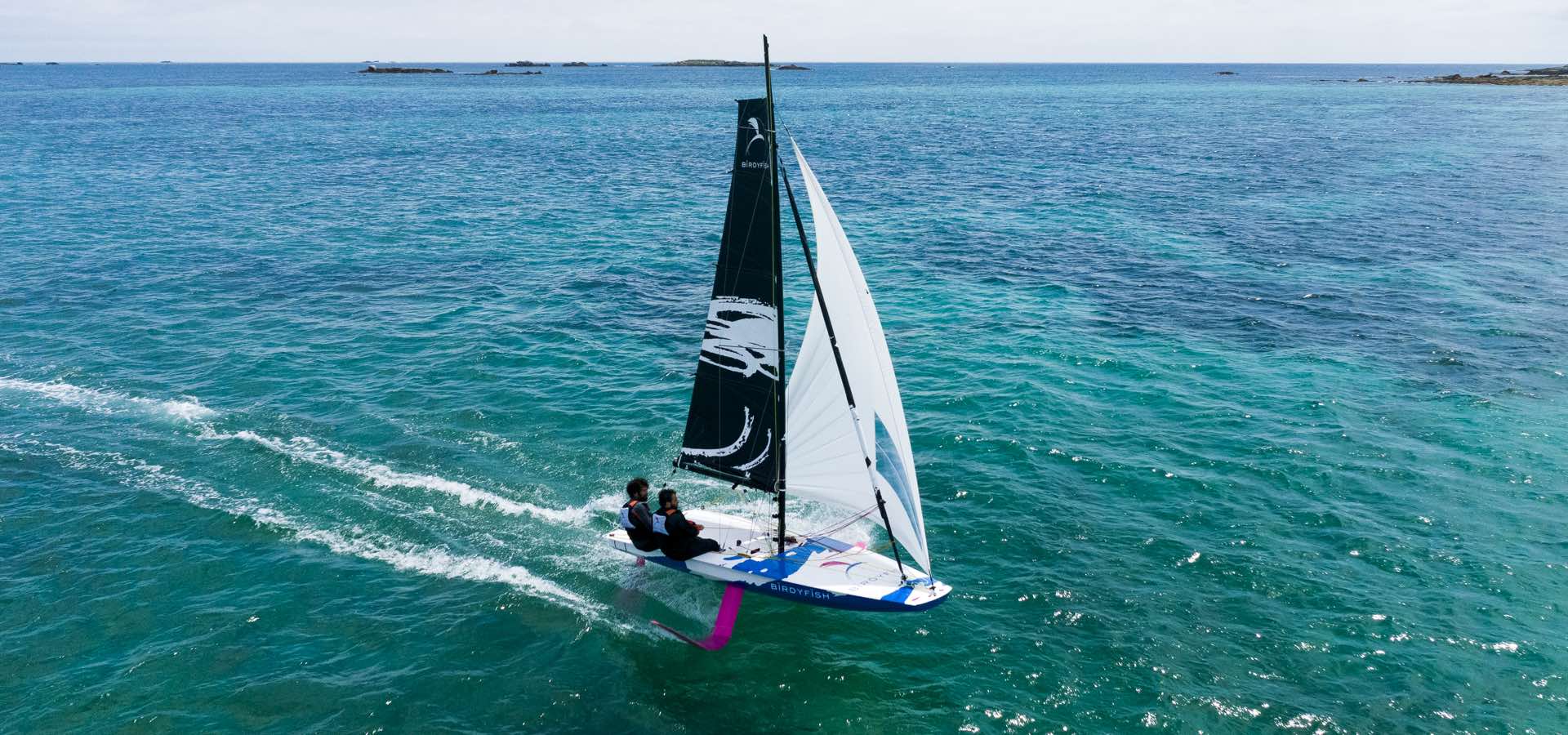 BitfyFish Foiling Segeljolle unter Gennaker mit zwei Personen im Foiling Modus, Luftaufnahme